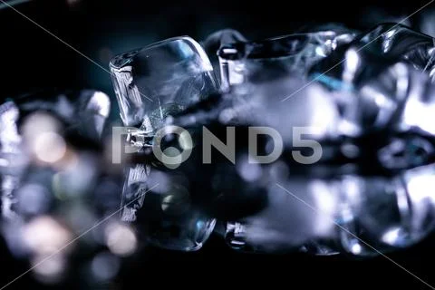 Pile of different ice cubes on reflection table on black background ...