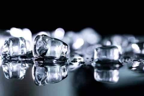 Pile of different ice cubes on reflection table on black background Stock Photos