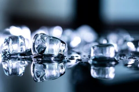 Pile of different ice cubes on reflection table on black background Фото