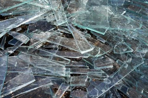 A pile of different sharp pieces of broken glass lying on the ground. Stock Photos