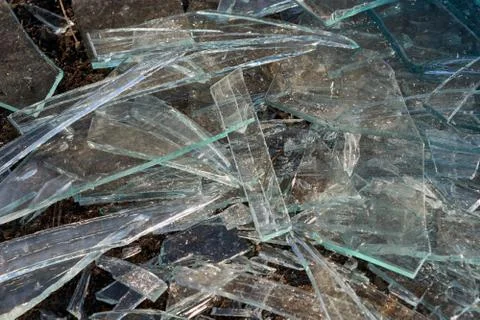 A pile of different sharp pieces of broken glass lying on the ground. Foto stock