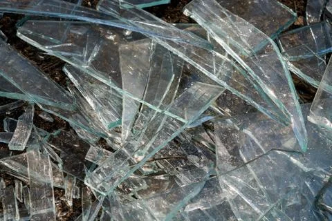 A pile of different sharp pieces of broken glass lying on the ground. Foto stock