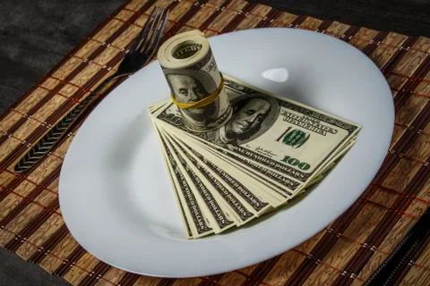 A pile of dollars on a white plate on a server side table Stock Photos