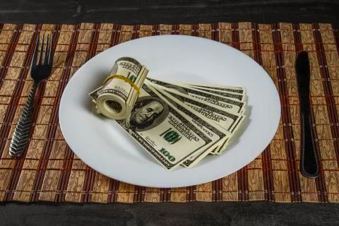 A pile of dollars on a white plate on a server side table Stock Photos