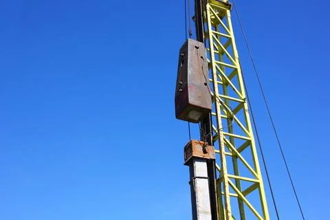 Pile driving crane working in construction site against blue sky Foto stock