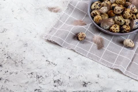 Pile of Easter quail eggs on gray fabric rag on concrete background Stock Photos