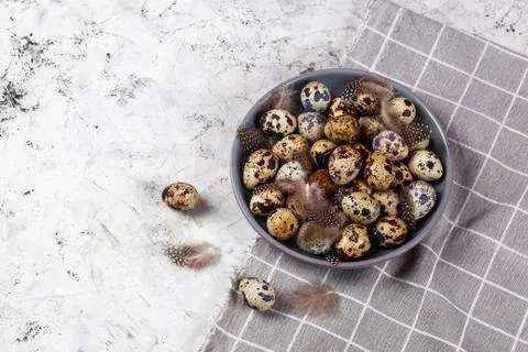 Pile of Easter quail eggs on gray fabric rag on concrete background Stock Photos