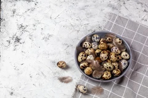 Pile of Easter quail eggs on gray fabric rag on concrete background Stock Photos