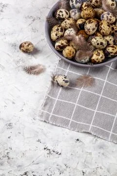 Pile of Easter quail eggs on gray fabric rag on concrete background Foto stock