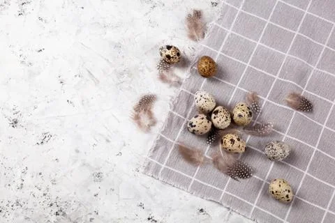 Pile of Easter quail eggs on gray fabric rag on concrete background Stock Photos