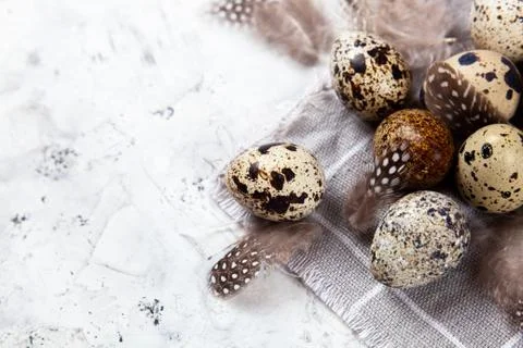 Pile of Easter quail eggs on gray fabric rag on concrete background Stock Photos