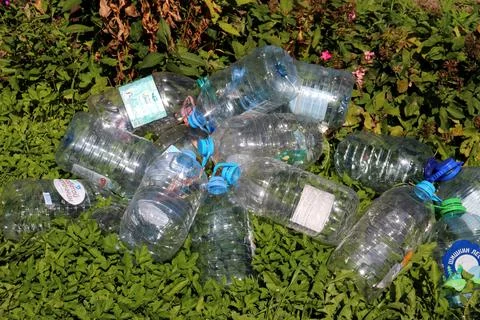 A pile of empty plastic five-liter bottles with water caps on the grass Stock Photos