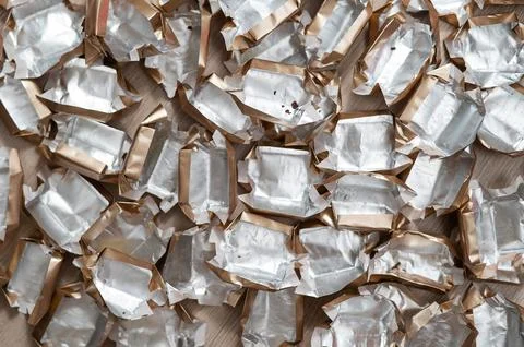 Pile of empty silver-gold candy wrappers. Top view. Stock Photos