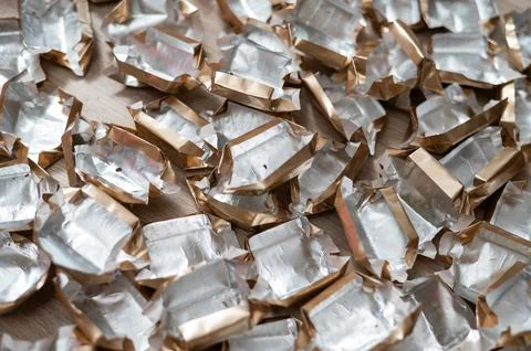 Pile of empty silver-gold candy wrappers. Top view. Stock Photos