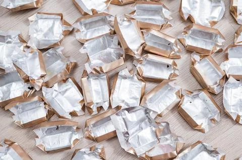 Pile of empty silver-gold candy wrappers. Top view. Stock Photos
