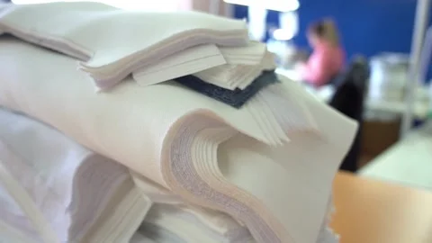 Pile of fabrics lies on brown table against blurry tailor Stock Footage 136400560