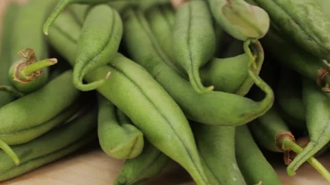 A pile of fresh green beans, a staple food ingredient, rests on a wooden cutting Stock Footage 275845133