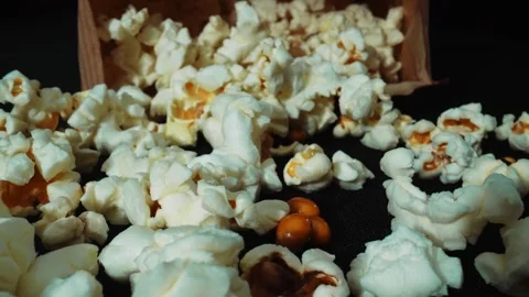 A pile of fresh popcorn falling from paper box and scattering at floor. Pabulum. Stock-Footage 289308772