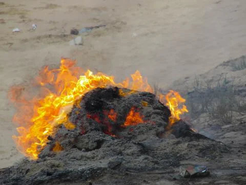 The pile of garbage is being burned to ashes on the beach Stock Photos