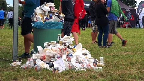 A pile of garbage next to an overfilled garbage bin at a race event Vídeo Stock 82233500
