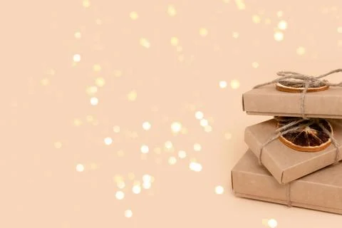 Pile of gift boxes on a beige background with glowing gold bokeh. Stock Photos