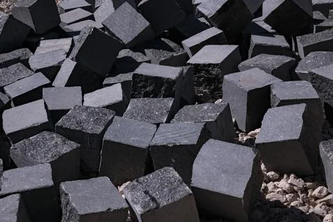 Pile of grey granite cobblestone blocks for paving at construction site Stock Photos