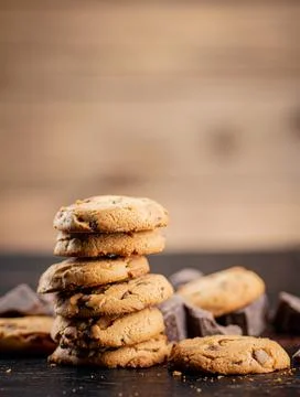 Pile of homemade cookies with pieces of milk chocolate on the table. Stock Photos
