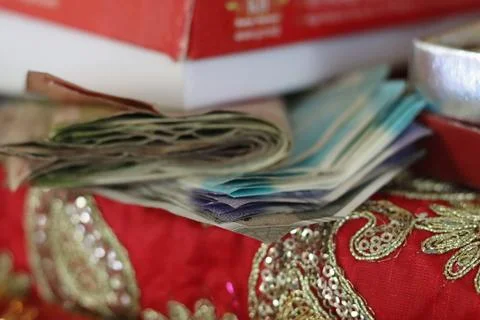 A pile of Indian currency notes placed on a red decorative cloth Stock Photos