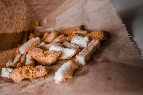 A pile of long fried white bread croutons lie in craft paper. Stock Photos