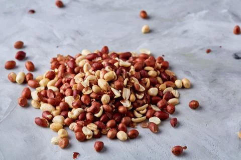 Pile of mixed raw peelled peanuts isolated on white textured background Stock Photos