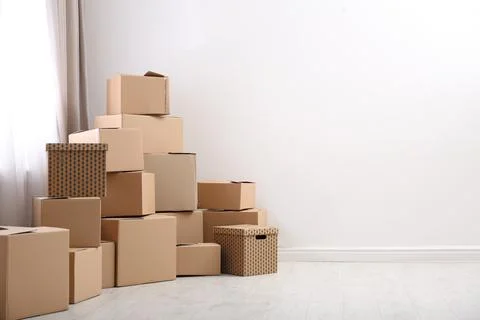 Pile of moving boxes in empty room, space for text Stock Photos