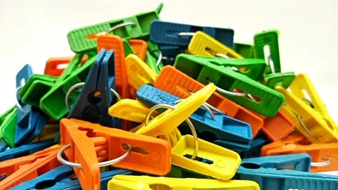 A pile of multi color plastic laundry clips rotating on the white background Stock Footage 305894409