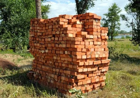 A pile of new red bricks at construction site sitting on wooden flat. A pi... 写真素材