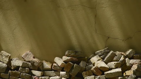 Pile of old bricks stacked in house back yard, leaning on to yellow wall Vídeos de archivo 211613595