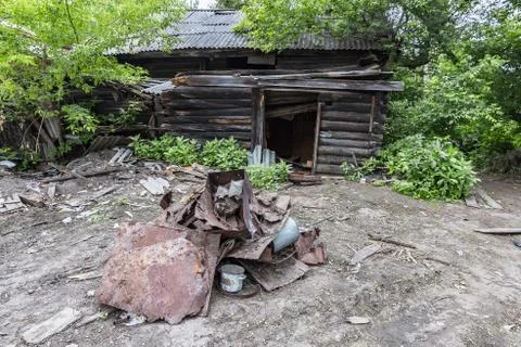 A pile of old rusty garbage in front of an abandoned wooden house Stock Photos