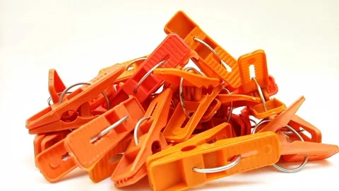 A pile of orange laundry clips rotating on the white background, plastic clips Stock Footage 306038712