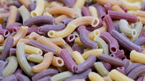 A pile of organic, vegetable-flavored, multi-colored cylindrical tube pasta. Stock Footage 296558810
