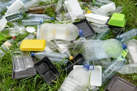 Pile of plastic garbage on the grass in the forest. plastic containers Stock Photos