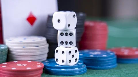 A pile of poker chips and a stack of dice on a green table Stock Photos
