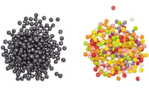 Pile of raw black beans next to colorful candy drops on white background Stock Photos