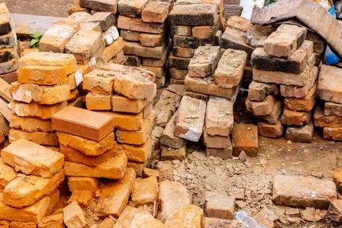 Pile of red bricks at a construction site in the city. Repair, industrial bri Stock Photos
