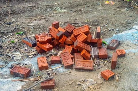 A pile of red bricks on a construction site, surrounded by dirt and debris... Foto stock