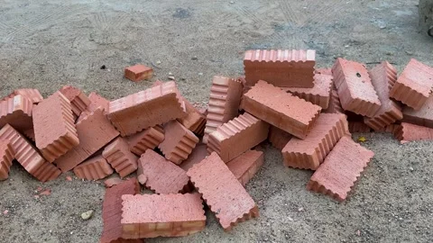 Pile of red ceramic bricks scattered on sandy ground at construction site Video stock 342438227