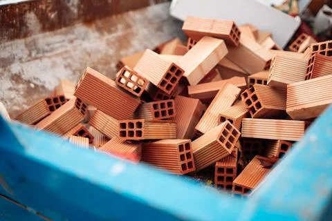 Pile of red clay construction bricks inside industrial container at buildin.. Stock Photos