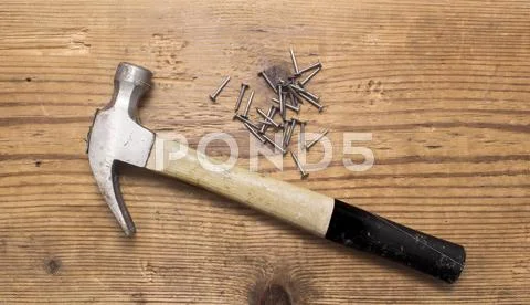 Pile of rivets, nails and hummer on wooden ground, closeup Stock Photos