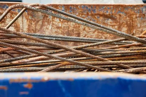 Pile of rusty rebar bars creating a textured pattern inside a metal skip Stock Photos