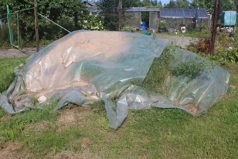 A pile of sand covered with a translucent plastic sheet in the backyard Stock Photos