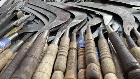 A pile of sharp tools such as knives, machetes, axes, sickles, metal sickles Stock Photos