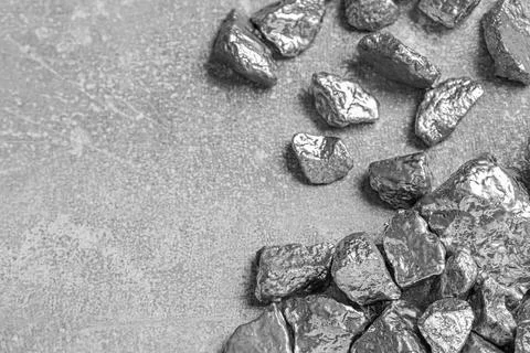 Pile of silver nuggets on light grey table, above view. Space for text Stock Photos