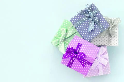 Pile of a small colored gift boxes with ribbons lies on a violet background Stock Photos